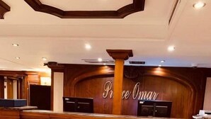 Un comptoir d’accueil avec un revêtement en bois et une enseigne portant l’inscription « Prince Omar ».