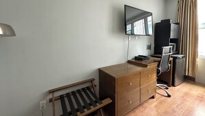 A compact room with a wooden dresser, a desk, a chair, a television mounted on the wall, and a window with curtains. - King bed suite in the heart of downtown, festive atmosphere (Montréal)