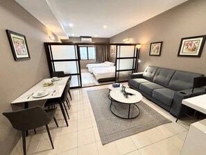 A modern hotel room with a dining area, a sofa, a coffee table, and a bed with a view.