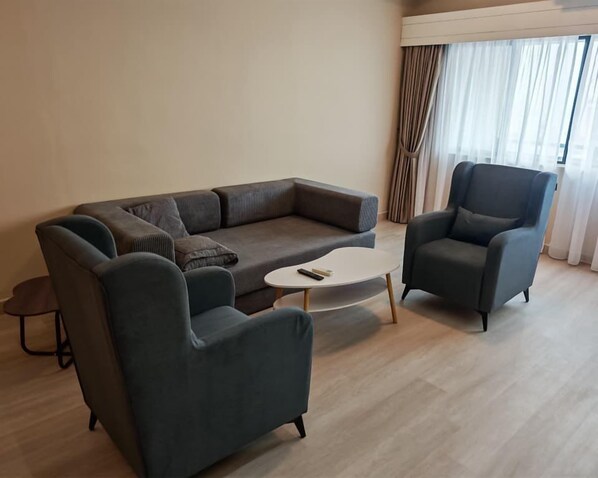 A modern living room with a sectional sofa, two armchairs, and a small coffee table.