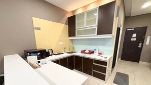 A modern kitchen with a microwave, sink, and cabinets. There is a small table with a cup and a box of tissues. - Cempaka Apartment By Easy Nap (Kuala Lumpur)