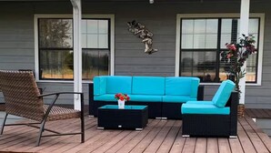 A covered outdoor seating area with a sofa and chairs, a small table, and a decorative wall piece. - Skyblue Ranch, Peaceful Getaway with Pool!Pets! (Terrell)
