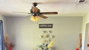 A dining area with a white table, blue velvet chairs, and a ceiling fan. - Skyblue Ranch, Peaceful Getaway with Pool!Pets! (Terrell)