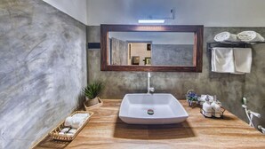 Une salle de bain avec un grand miroir, un lavabo rectangulaire, un meuble-lavabo en bois et des serviettes rangées sur un porte-serviettes.