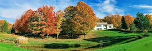 Set amidst a serene landscape with autumnal foliage, this two-story residence offers a peaceful retreat.