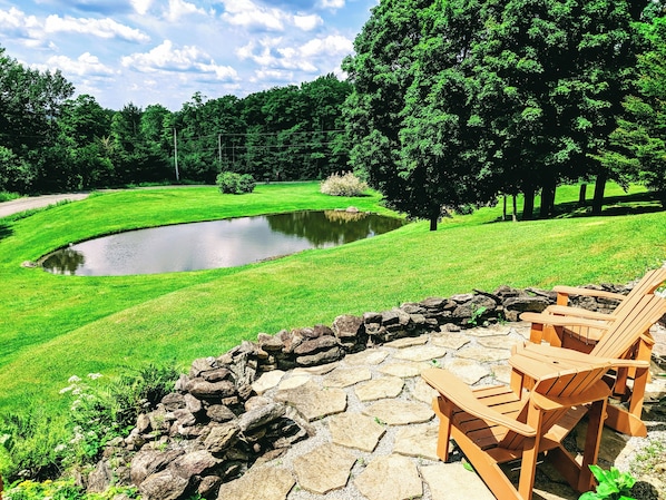 Relax in a serene outdoor setting surrounded by lush greenery and a tranquil pond.