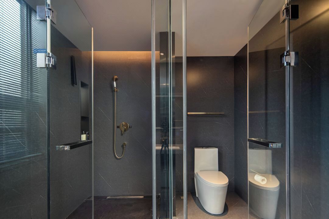 A modern bathroom with a glass-enclosed shower, a toilet, and a vanity with a mirror.