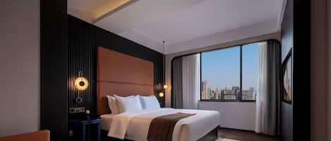 A modern hotel room with a large bed, a nightstand, a desk, and a view of the city.