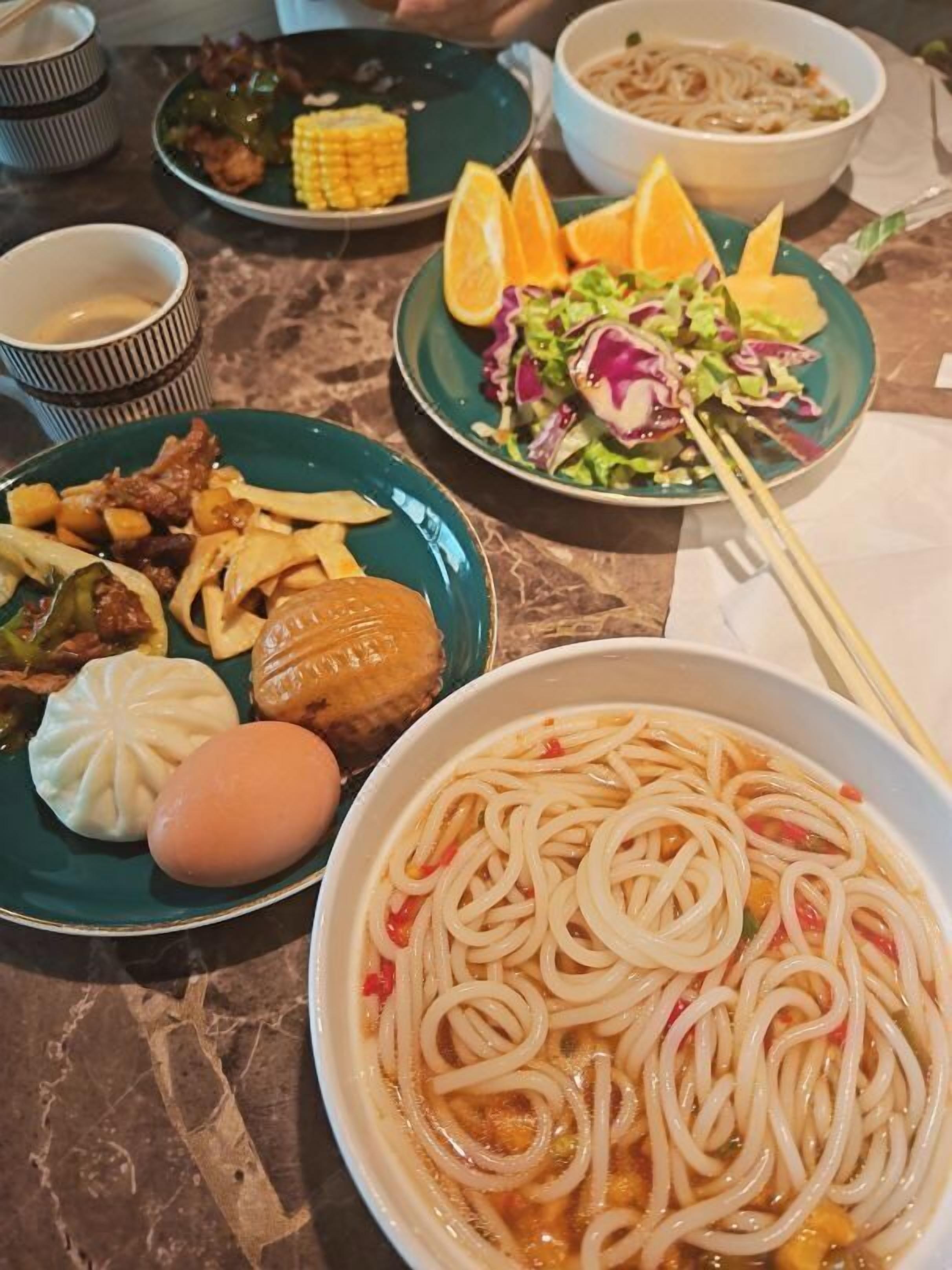A variety of dishes including noodles, dumplings, and a salad, suggesting a diverse meal selection.