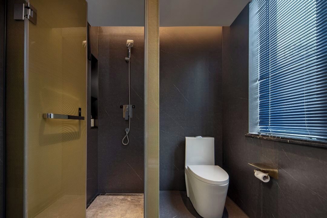 A modern bathroom with a glass-enclosed shower, a toilet, and a window with blinds.