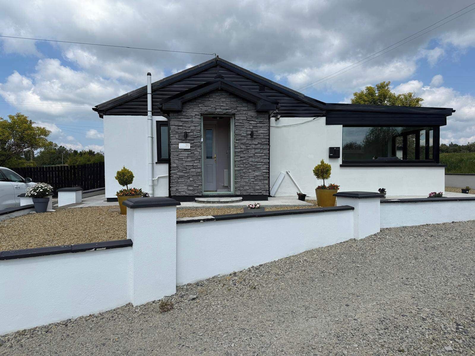 A modern two-story house with a stone facade, a grey door, and a black roof.