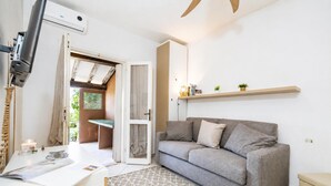 Una sala de estar moderna con un sofá gris, una mesita con lámpara y un ventilador de techo.