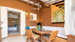 Un comedor con mesa y sillas de madera, un sofá y un ventilador de techo.