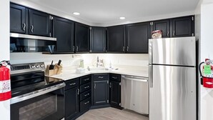 A modern kitchen with black cabinets, stainless steel appliances, and a white countertop. - Newly Remodeled 1BR | Shuttle, Fireplace, Amenities in the Heart of Killington (Killington)