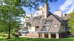 A multi-story building with a clock on the facade, multiple balconies, and a green awning over the entrance. - Newly Remodeled 1BR | Shuttle, Fireplace, Amenities in the Heart of Killington (Killington)