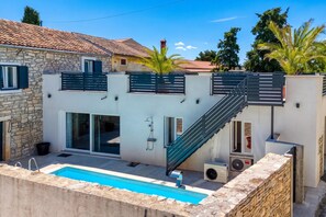 A modern villa with a swimming pool, a stone wall, and a staircase leading to a second floor. - Villa Galant with Pool and Sauna, Maružini, Croatia (Maružini)