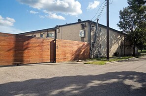 A building with a brick exterior, a gated entrance, and a satellite dish on the roof. - Montrose Chic Studio! Medical Center 12 (Houston)