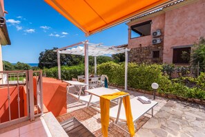 Un patio al aire libre con una pérgola, mesas y sillas.