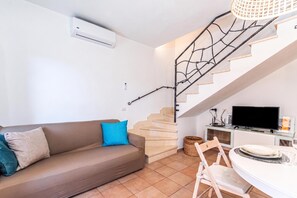 A living room with a sofa, a TV, a staircase, and a dining area. - House Sardinia La Dolce Vita, Budoni, Italy (Budoni)