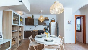 Een moderne keuken met een ronde eettafel, houten stoelen en een hanglamp.