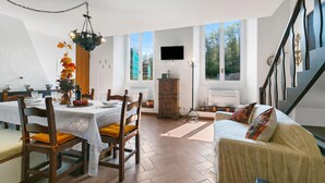 En matplats med ett bord dukat för två personer, en soffa, en kristallkrona och en tv som är monterad på väggen.