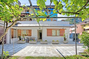 Un edificio residencial con patio, mobiliario exterior y plantas en macetas.