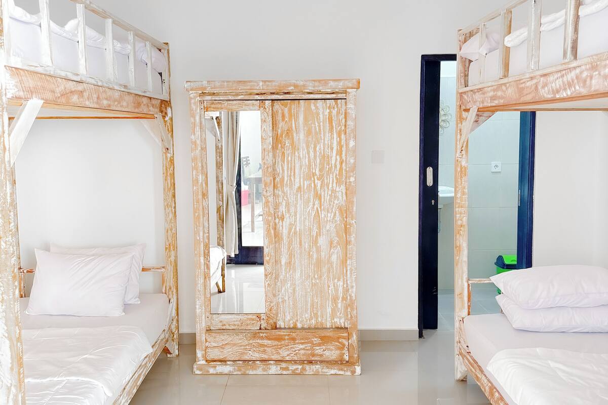 Ein Zimmer mit zwei Etagenbetten, einem großen Spiegel und einer Tür zu einem weiteren Raum.