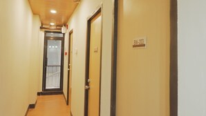 A hallway with doors labeled B-W-203, wooden floors, and a ceiling with recessed lighting. - Brightwood Hotel & Residences (Manila)