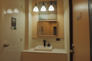 A bathroom with a sink, mirror, and three pendant lights. - Brightwood Hotel & Residences (Manila)