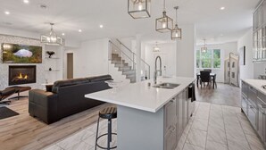 A modern kitchen with a large island, stainless steel appliances, and pendant lighting.