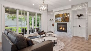 A modern living room with a fireplace, leather sofa, and round coffee tables.
