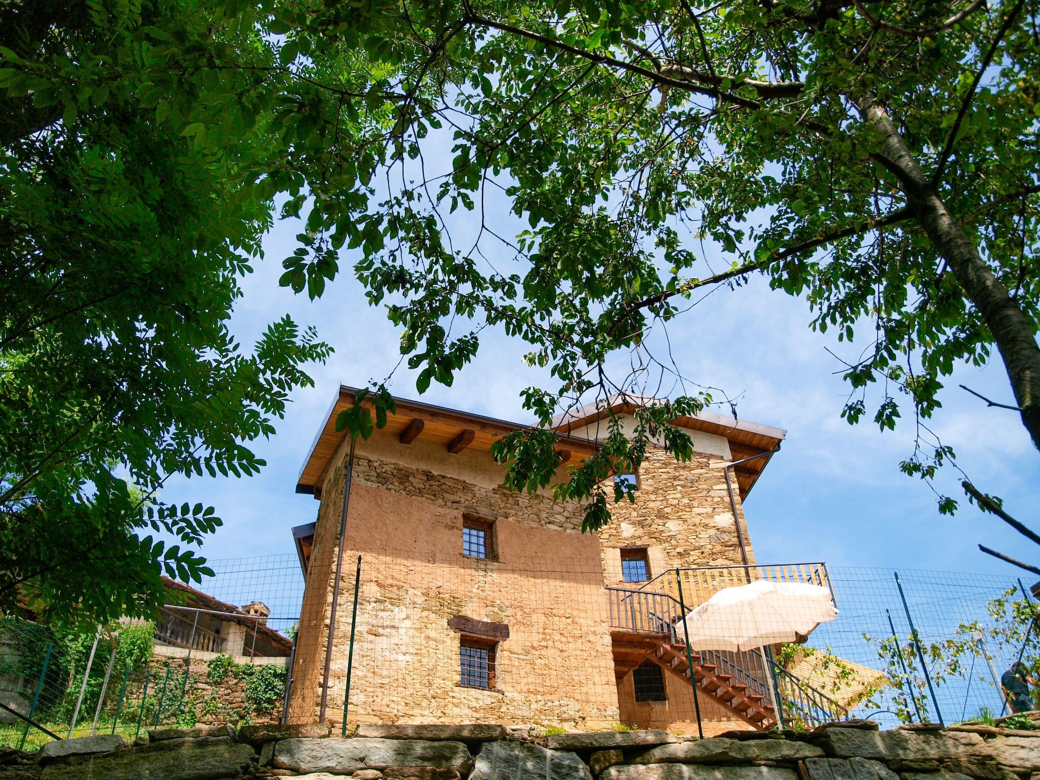 A stone building with a wooden balcony and a staircase leading to the entrance.