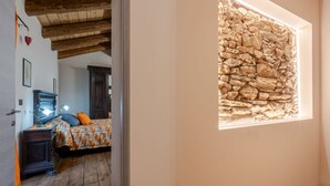 A bedroom with a wooden ceiling, a stone wall, and a bed with a patterned bedspread. - Poderi Alugi Serravalle by Interhome (Piasco)