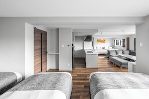 A modern hotel room with a wooden wardrobe, a kitchenette, a sofa bed, and a dining table.