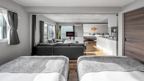 Ett modernt hotellrum med en stor säng, en soffa, en TV och ett litet kök.