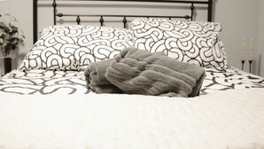 A neatly made bed with patterned bedding, a metal headboard, and a framed picture on the wall. - The Retro Apartment in Revere with outdoor area (Revere)