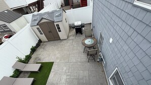 A patio area with a grill, a round table, and a seating arrangement. - The Retro Apartment in Revere with outdoor area (Revere)