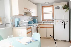 A modern kitchen with white cabinets, a blue countertop, and a refrigerator. - The Retro Apartment in Revere with outdoor area (Revere)