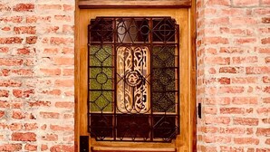 Una puerta de madera con un panel de vidrio y una placa con número arriba.