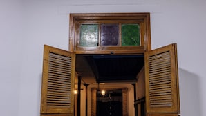 Un pasillo con contraventanas de madera y suelo de baldosas.