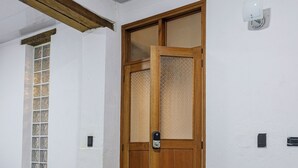 Una habitación con una puerta de madera, una ventana con diseño de cuadrícula y un piso de baldosas.