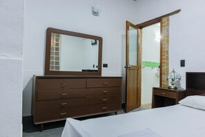 Un dormitorio con un aparador de madera, una cama, una mesita de noche y un espejo.