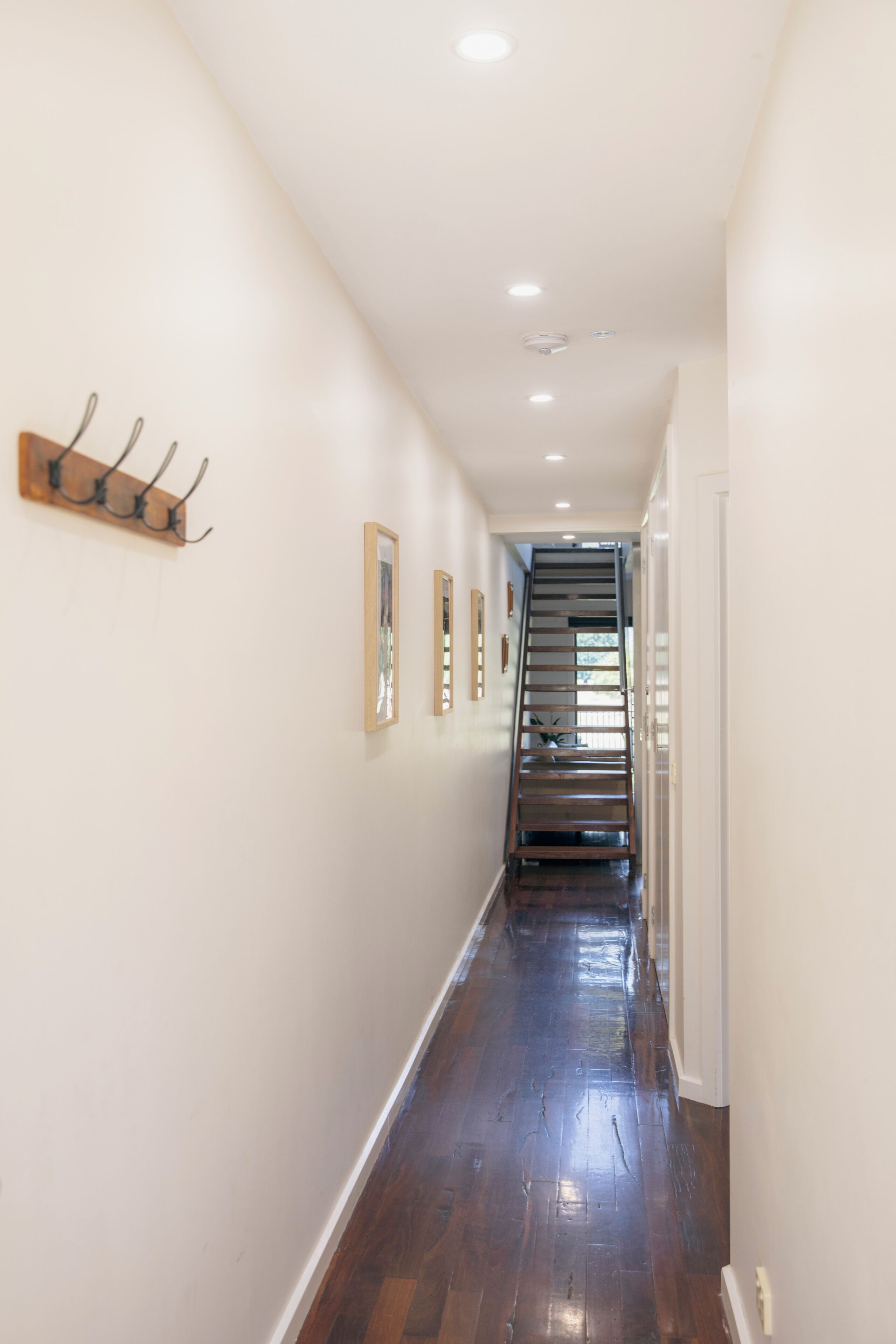 Ein Korridor mit Holzboden, weißen Wänden und einer Treppe, die zu einer anderen Etage führt.