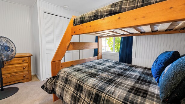 A bunk bed with a plaid bedspread, a wooden dresser, and a window with curtains. - Barton Bungalow (Sugarloaf)