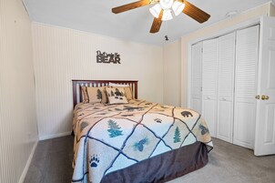 A bedroom with a bed, a ceiling fan, and a wardrobe.