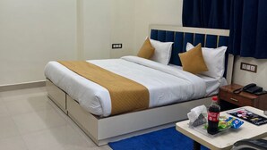 A hotel room with a bed, a desk, a chair, a nightstand, a phone, a bottle of Coca-Cola, and a magazine. - Hotel Aero Fly (New Delhi)