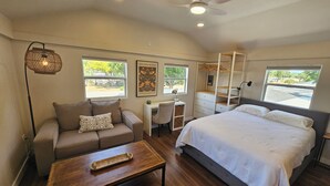 Un dormitorio con cama, escritorio, silla, sofá y ventilador de techo.