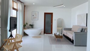 A modern bathroom with a freestanding bathtub, a vanity with a mirror, and a shower area. - BanyakasSirindhron (Sirindhorn)