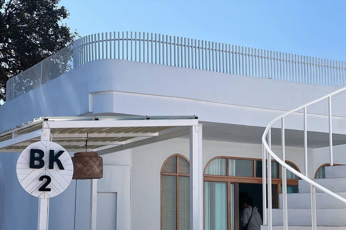 Un edificio moderno con fachada blanca, un acceso cubierto y un cartel que indica la habitación número 2.