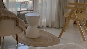A room with a view of the beach, a white chair, a small table, and a TV on the wall. - BanyakasSirindhron (Sirindhorn)